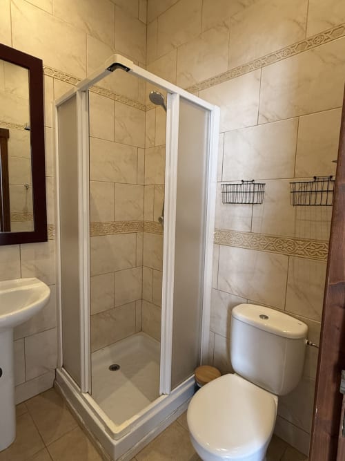Baño moderno con ducha de esquina, inodoro y lavabo en Hotelito Oliva Pensión en Oliva, España