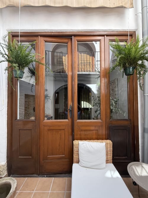 Puertas francesas de madera con plantas de helecho en habitación de Hotelito Oliva Pensión, Oliva España