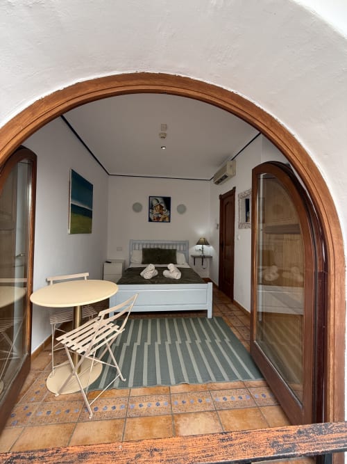 Acogedor dormitorio doble en Hotelito Oliva Pensión en Oliva, España, con cama blanca, escritorio pequeño, alfombra rayada y baldosas de terracota