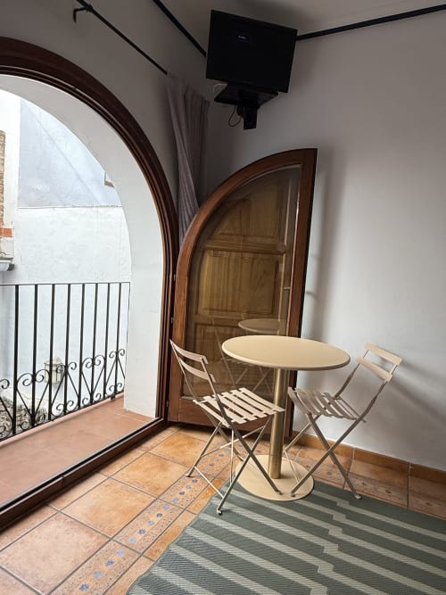Habitación moderna de hotel con mesa redonda, sillas y puerta de madera arqueada en Hotelito Oliva Pensión, Oliva, España