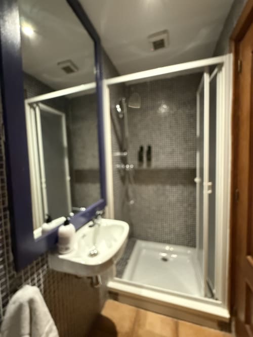 Baño moderno con ducha, lavabo y espejo en Hotelito Oliva Pensión en Oliva, España