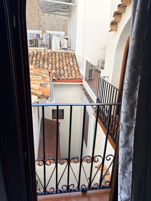 Vista del balcón de la Habitación 201 en Hotelito Oliva Pensión en Oliva, España, con vistas al patio y tejados de barro