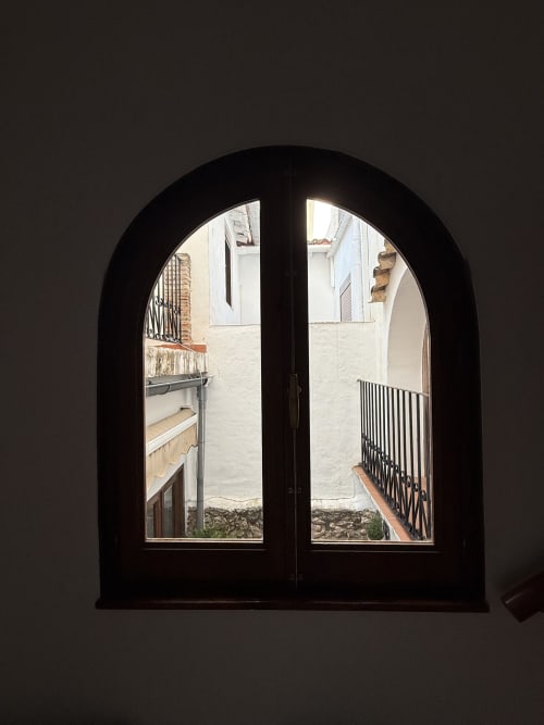 Puertas dobles negras arqueadas con cristales que abren a un patio del Hotelito Oliva Pensión en Oliva, España