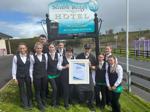 Hotel staff at Sliabh Beagh Hotel in Monaghan holding award certificate outside main entrance