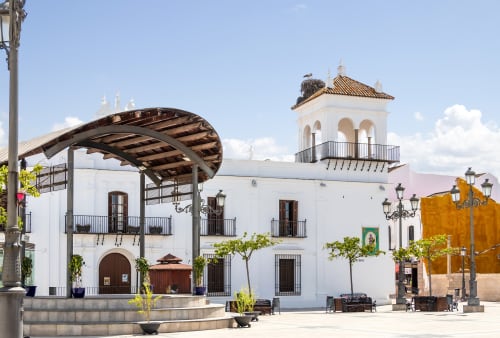 Patio del Hotel Plaza Chica en Cartaya con arquitectura colonial blanca, campanario y pórtico cubierto