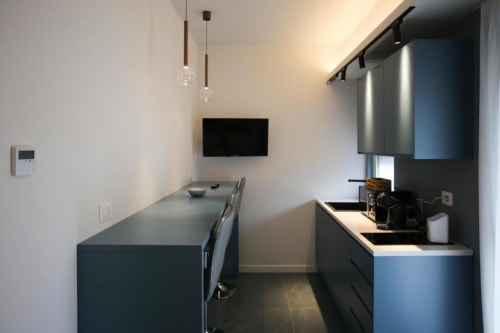 Cucina moderna a Totonno's Rooms a Tropea con mobili scuri, lampade a sospensione e TV a parete