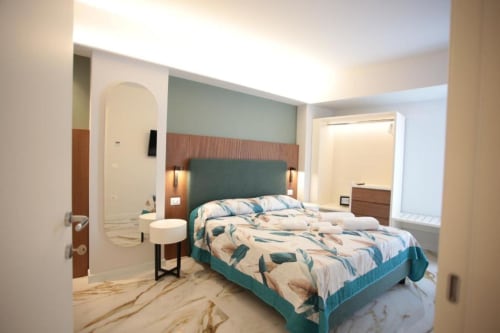 Camera moderna di Totonno's Rooms a Tropea con testata color turchese, biancheria a motivi e bagno ensuite
