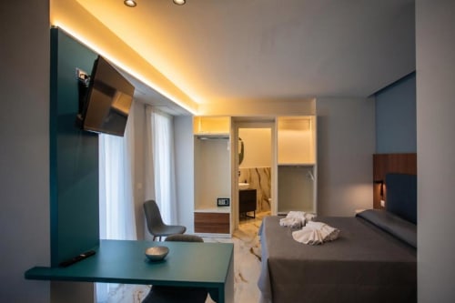 Camera moderna a Totonno's Rooms a Tropea con letto, scrivania e bagno illuminati da una calda luce ambientale