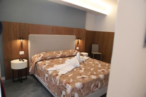 Camera moderna presso Totonno's Rooms a Tropea con letto queen, testata in legno, lampade comodino e arredi contemporanei