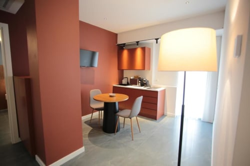 Moderna angoletta di cucina della camera a Totonno's Rooms a Tropea con muri color corallo, tavolo rotondo e illuminazione ambientale