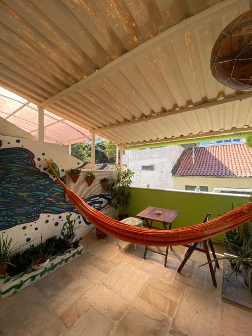 Terraço colorido no Hostel New Ipanema com rede, paredes verdes e vista da cidade do Rio de Janeiro