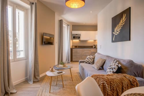 Modernes Apartment in Cannes mit grauem Sofa, Holzmöbeln, Küche und Stadtblick