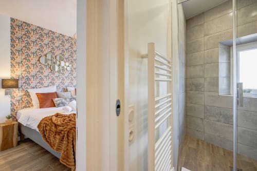 Modernes Schlafzimmer in einer Cannes-Wohnung mit gemusterter Akzentwand, eigenem Badezimmer und zeitgenössischen Möbeln
