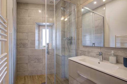 Modernes Badezimmer in luxuriöser Cannes-Wohnung mit begehbarer Dusche, schwebendem Waschtisch und Stadtblickfenster