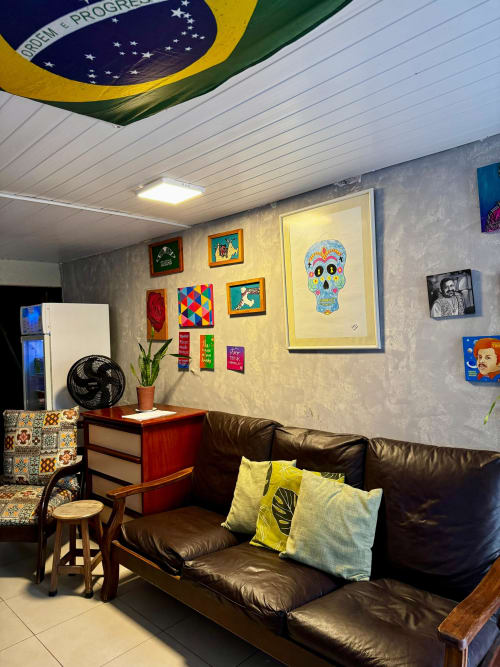 Aconchegante área comum do Hostel New Ipanema com sofá de couro preto, teto com bandeira brasileira e arte colorida nas paredes.