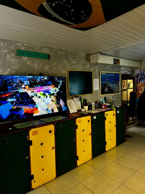 Área comum do Hostel New Ipanema Rio de Janeiro com display de imagem térmica e armários de armazenamento amarelo-verde