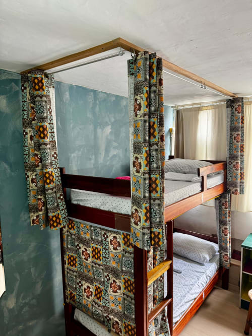 Cama com dossel colorida e estampada no dormitório feminino do Hostel New Ipanema, Rio de Janeiro, com estrutura de madeira e detalhes decorativos