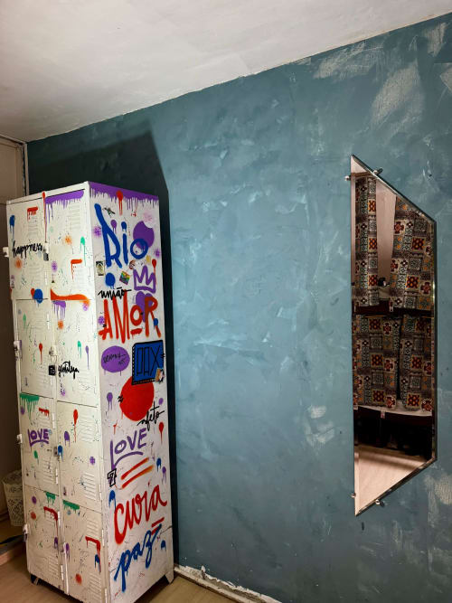 Geladeira colorida com grafite e parede azul no quarto de hostel no Rio de Janeiro com armário espelhado