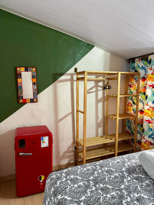 Quarto privado na Pousada New Ipanema com geladeira vermelha vintage, prateleiras de madeira e decoração colorida no Rio de Janeiro