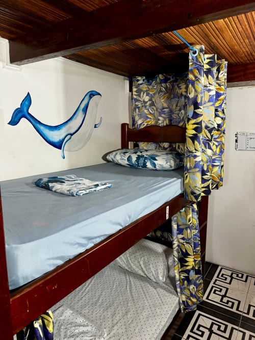Beliche com painel de baleia azul e cortinas florais em dormitório compartilhado do Hostel New Ipanema, Rio de Janeiro
