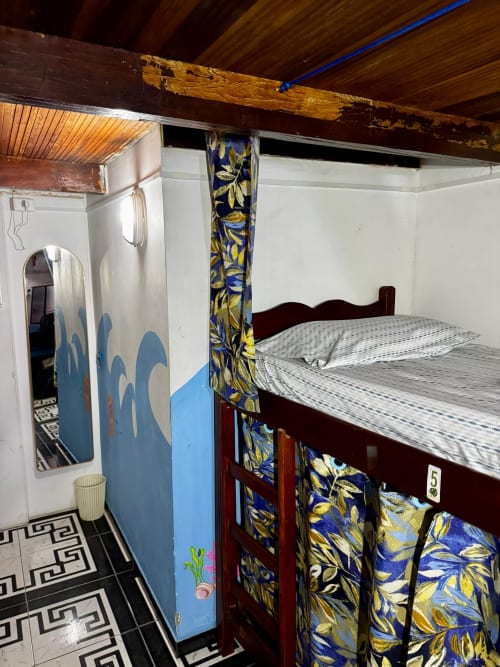 Quarto coletivo do Hostel New Ipanema, Rio de Janeiro com cama beliche, detalhes em azul e banheiro compartilhado
