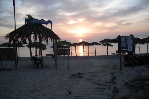 Tramonto sulla spiaggia del Resort Baia Cea a Bari Sardo con ombrelloni in paglia e passerelle in legno