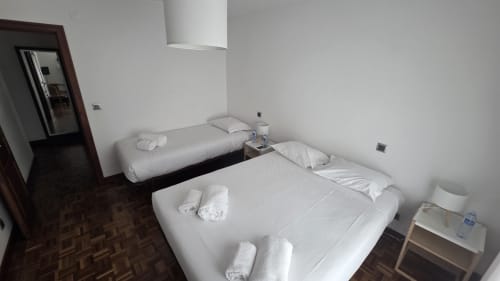Quarto limpo da dormitória no Hotel Slow Stay em Esposende com camas de casal e individual, roupa branca e comodidades modernas