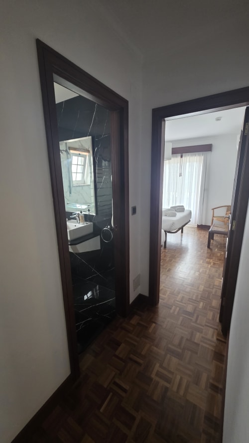 Corredor com portas escuras levando à casa de banho e quarto no Hotel Slow Stay em Esposende