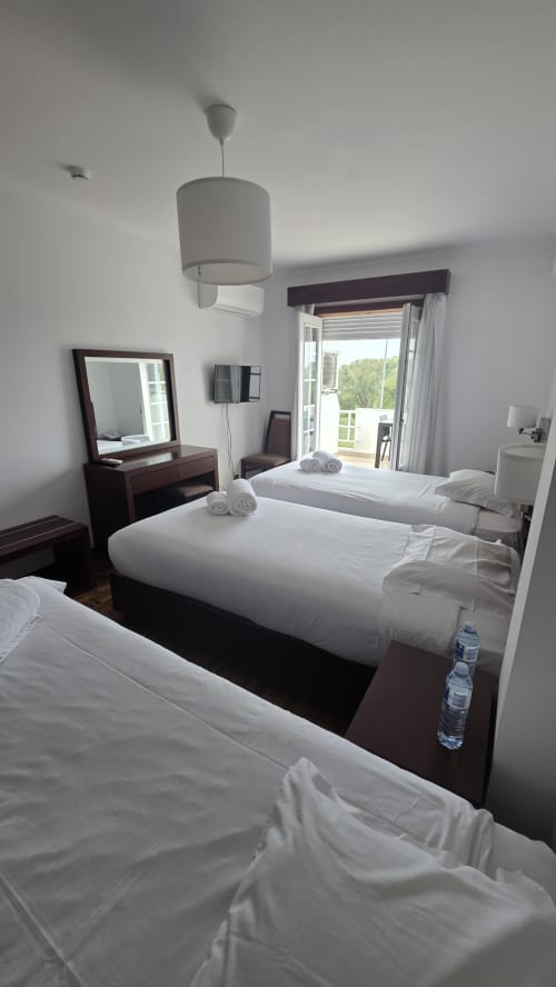 Quarto de hotel luminoso na Slow Stay com camas geminadas, móveis em madeira escura, varanda com vista para o rio em Esposende, Portugal