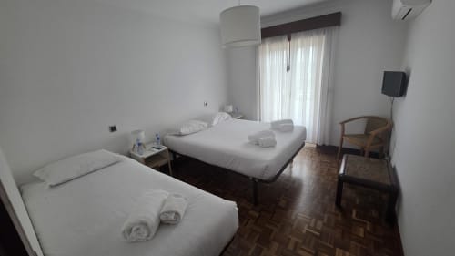 Espaçoso dormitório compartilhado no Hotel Slow Stay em Esposende com duas camas, TV, ar condicionado e acesso a vista para o rio através de portas de vidro