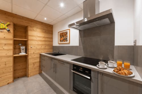 Cuisine moderne dans l'appartement La Gentiane au Domaine des Fleurs, Gérardmer, avec meubles gris et détails muraux en bois
