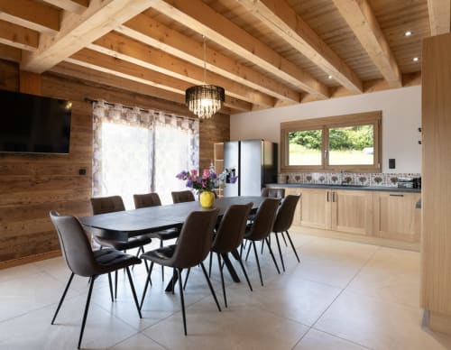Spacieuse salle à manger du chalet Le Cœur de Marie au Domaine des Fleurs à Gérardmer, avec poutres en bois et cuisine moderne