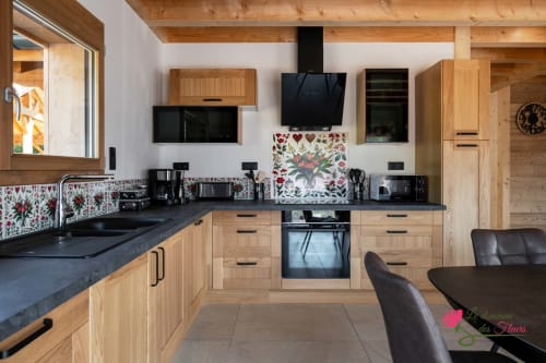 Cuisine moderne du chalet Le Cœur de Marie au Domaine des Fleurs à Gérardmer, avec meubles en bois et dosseret à motifs floraux