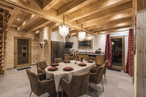 Élégante salle à manger de la villa La Reine des Prés au Domaine des Fleurs à Gérardmer, avec poutres apparentes et lustres en cristal