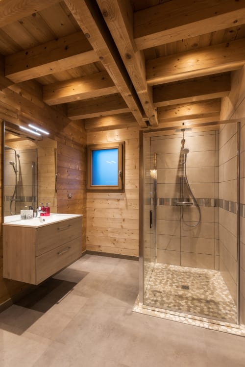 Salle de bain luxueuse du chalet La Reine des Prés à Le Domaine des Fleurs, Gérardmer, avec poutres en bois et douche vitrée