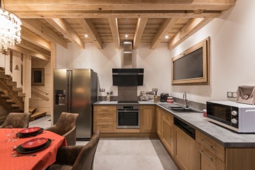 Cuisine moderne du chalet La Reine des Prés au Domaine des Fleurs à Gérardmer, avec poutres en bois et coin repas.