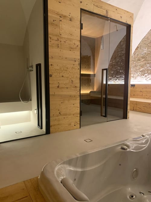 Lussuoso bagno spa di Villa Rosati con vasca idromassaggio, doccia in vetro e dettagli in legno a Sanzeno