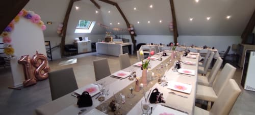 Élégante salle de banquet aux Gites De Flaubert avec table à manger, décor floral rose et ballons doré rose