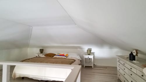 Chambre mansardée du bungalow Les Balcons D'Oyster Pond avec lits, tables de nuit, commode et parquet.