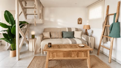 Lumineux séjour avec canapé rayé beige, table en bois, plante verte et accès vue mer aux Balcons D'oyster