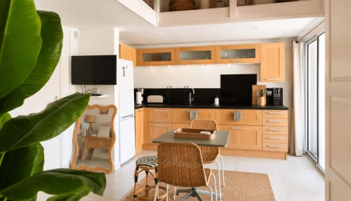 Cuisine moderne aux armoires en bois, plan de travail noir et table à manger du bungalow Les Balcons D'Oyster Pond, Saint-Martin