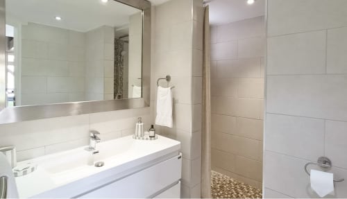Salle de bain moderne avec vanité blanche, grand miroir et douche carrelée au bungalow Les Balcons D'oyster Pond à Saint-Martin
