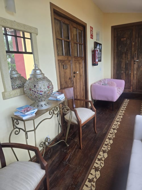 Salón suite del Hotel Rural la Raya 1866 en Tenerife con puertas de madera, sillón rosa, lámpara decorativa y acabados oscuros