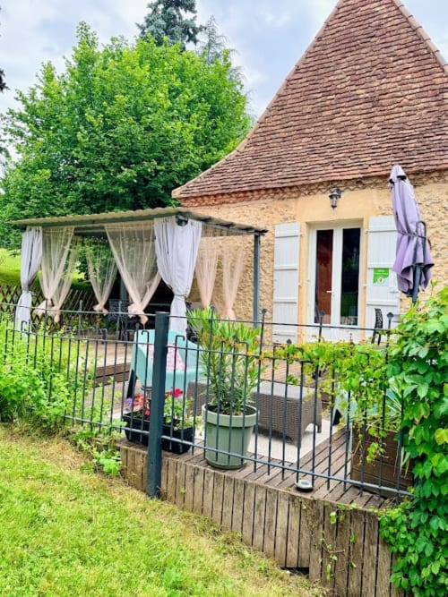 Charme d'une maison en pierre avec toit conique, terrasse aux voilages délicats et jardins verdoyants au Domaine le Manoir, Périgord Noir