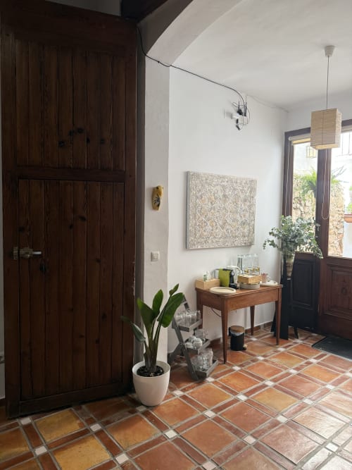 Entrada de Hotelito Oliva Pensión con puertas de madera oscura, piso de baldosa terracota, mostrador de madera y planta en maceta
