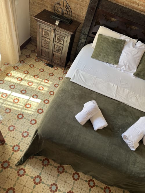 Habitación de la Pensión Hotelito Oliva en Oliva con cama verde aceituna, almohadas blancas, mueble de madera decorativo y azulejos de patrón
