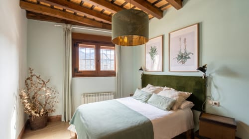 Dormitorio Cerezo en El Aserradero, La Alberca con cabecero verde, vigas de madera, luz colgante y vistas al jardín