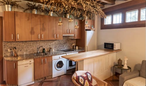 Cocina del apartamento Cerezo en El Aserradero, La Alberca, con muebles de madera, encimeras de granito, electrodomésticos modernos y jardín