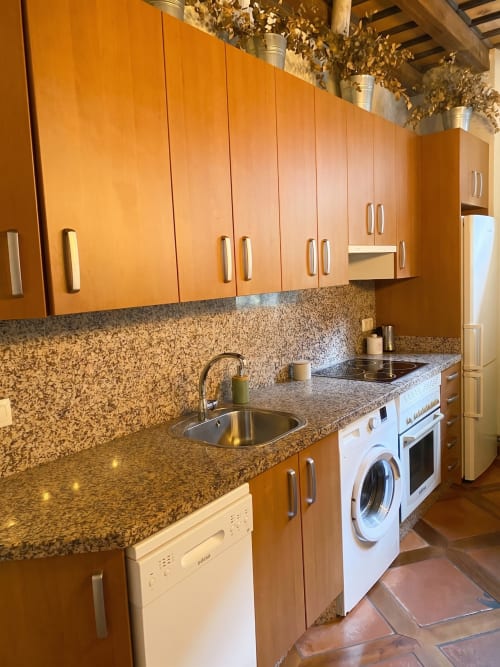 Cocina moderna del apartamento Cerezo en El Aserradero, La Alberca con muebles naranjas, encimeras de granito y acero inoxidable