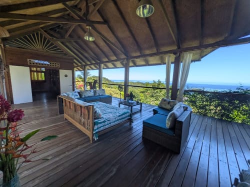 Terrasse de la villa Fare Tihi Moana avec vue sur l'océan, mobilier en bois et jardins tropicaux à Tumaraa
